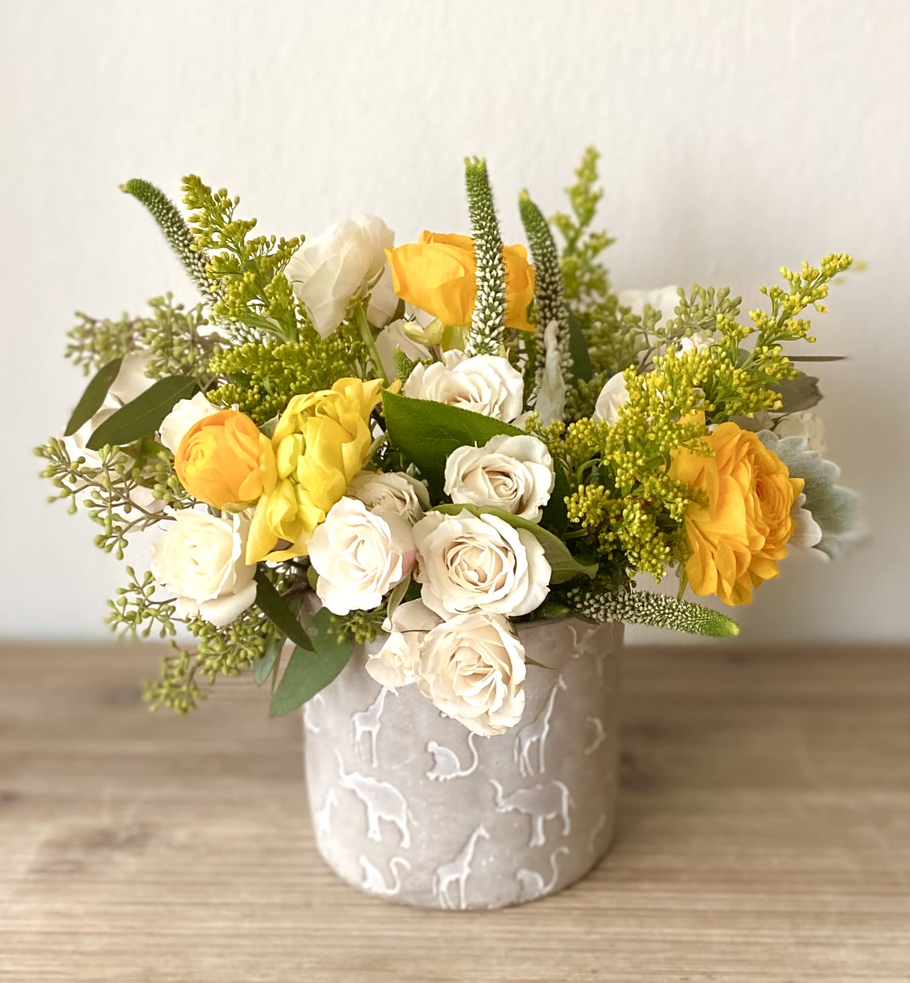 Yellow and white roses arranged in a patterned ceramic vase
