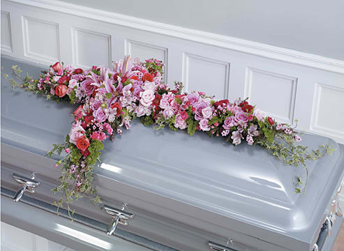 Pink and white floral spray arranged on a silver casket