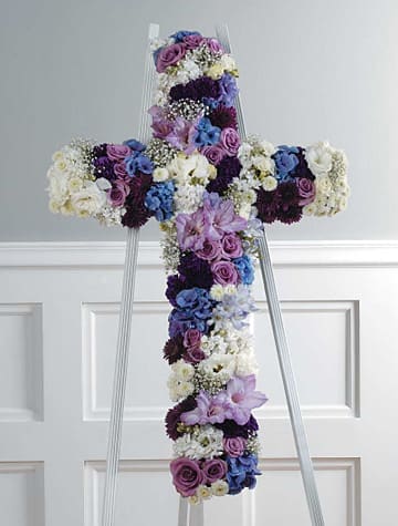 Floral cross arrangement on a standing easel with purple, blue, and white blooms