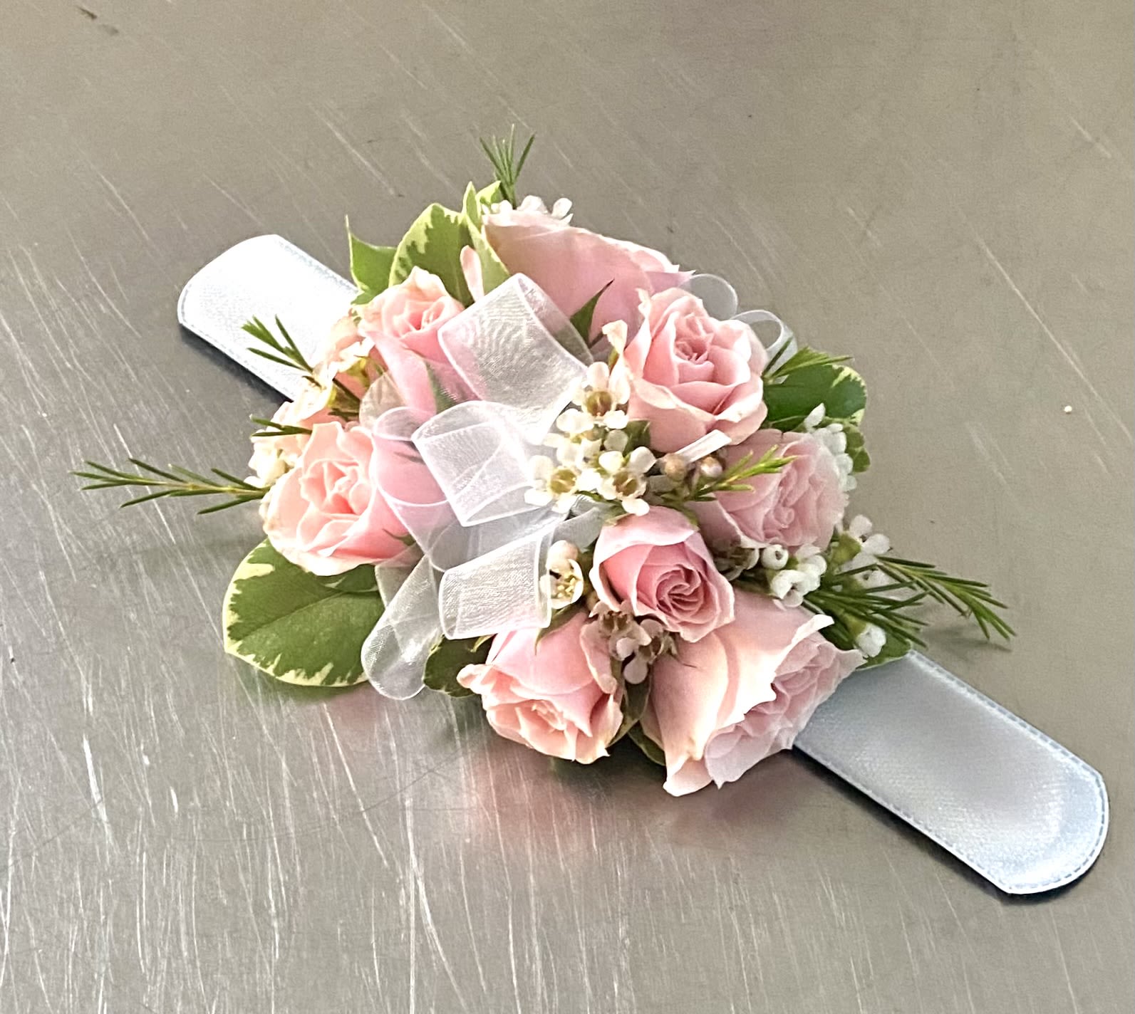 Pink rose wrist corsage with white ribbon on a satin band