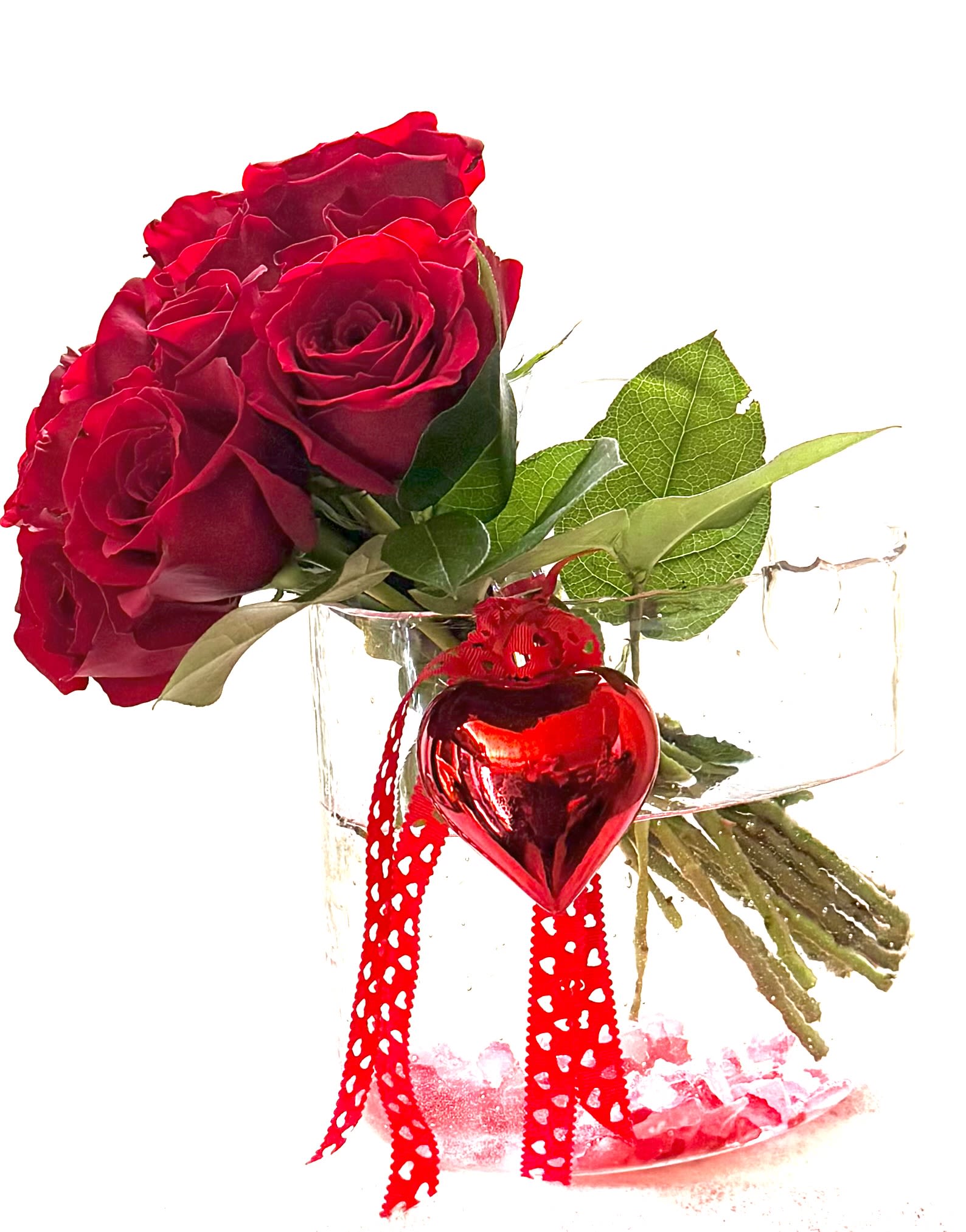 Red roses in a clear glass vase with a red heart ornament