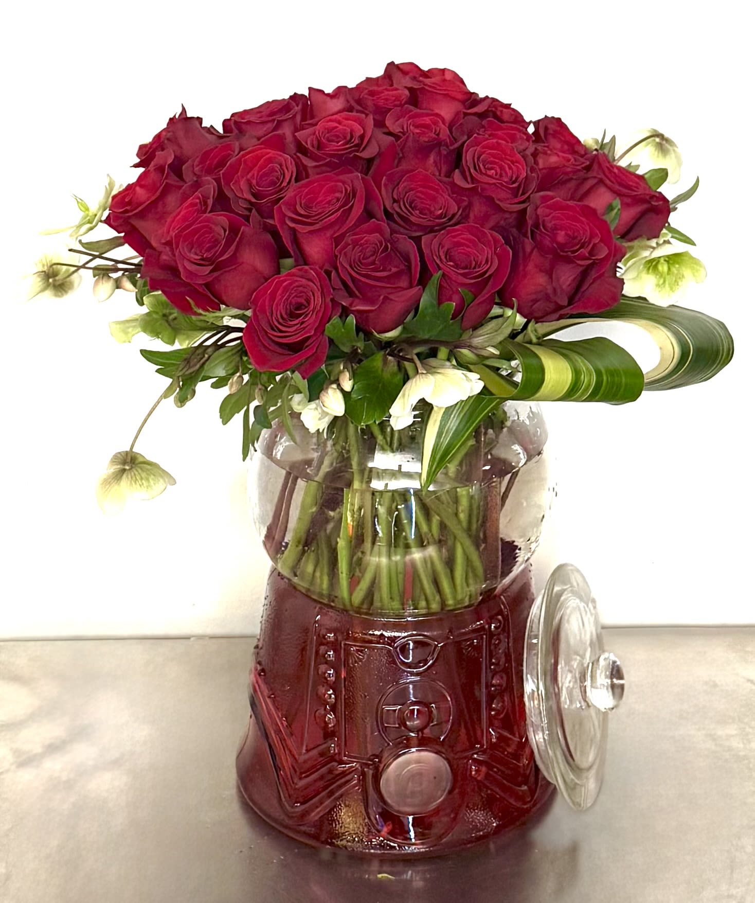 Red rose bouquet in a clear glass vase with a red base