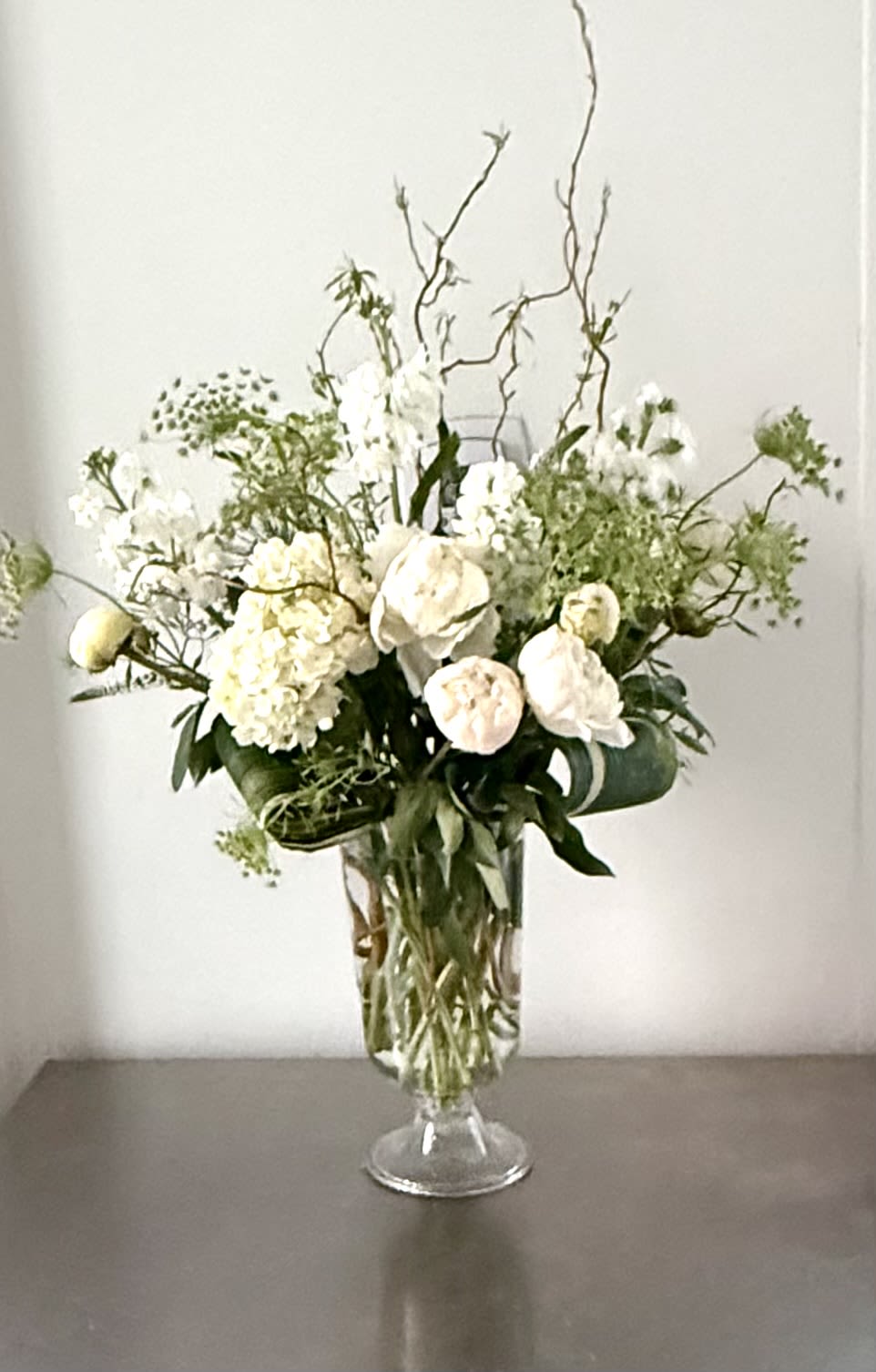 Pure Peony &amp; Lace - Celebrate the soft, romantic textures of the season with this breathtaking display of premium white peonies. This arrangement is a masterclass in monochromatic elegance, blending the "queen of flowers"—the peony—with airy, textural accents to create a look that is both modern and timelessly sophisticated.