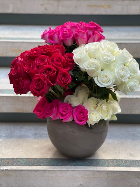 Three rose bouquets in pink, red, and white arranged in a round vase