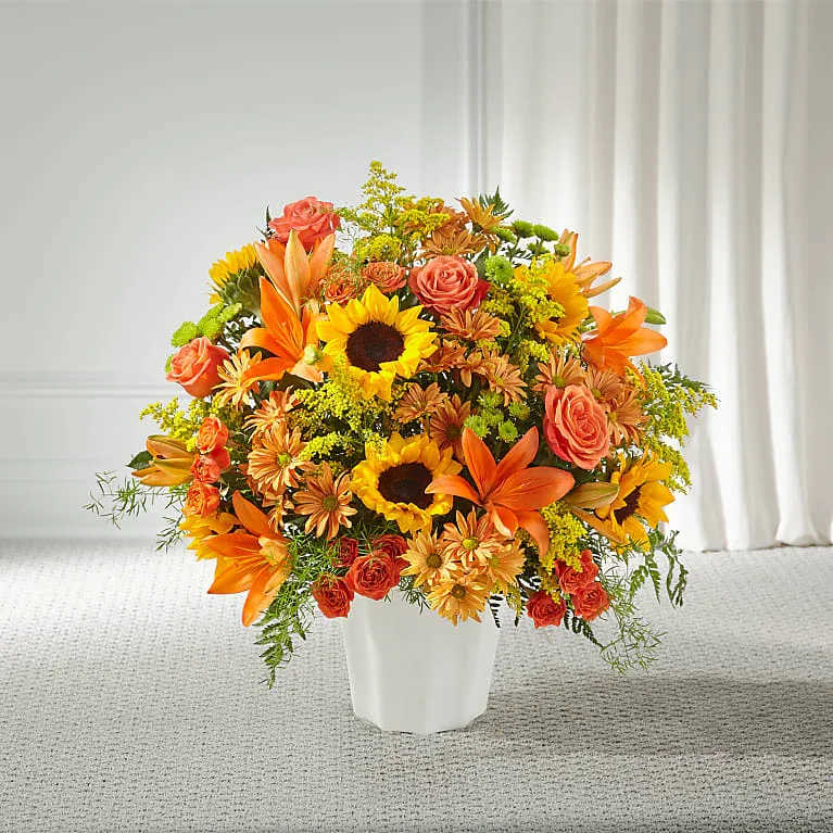 Orange and yellow mixed flower arrangement in a white vase