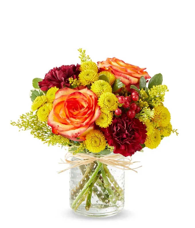 Bouquet of orange roses and yellow and burgundy flowers in a glass vase