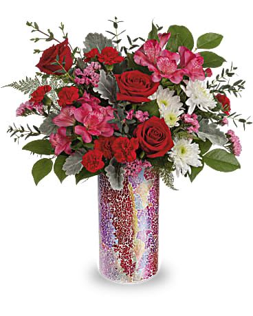 Red and pink mixed flower arrangement in a mosaic glass vase