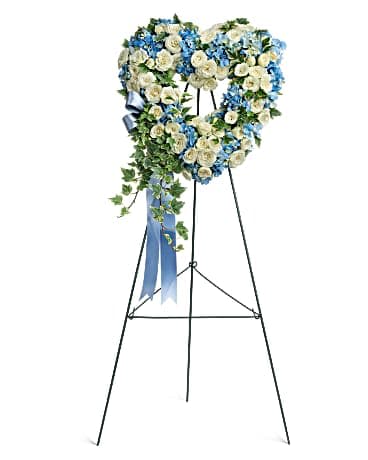 Heart-shaped floral wreath on a standing easel with blue and white flowers