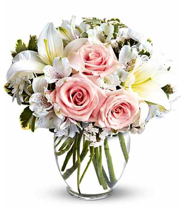 Pink roses and white lilies arranged in a clear glass vase