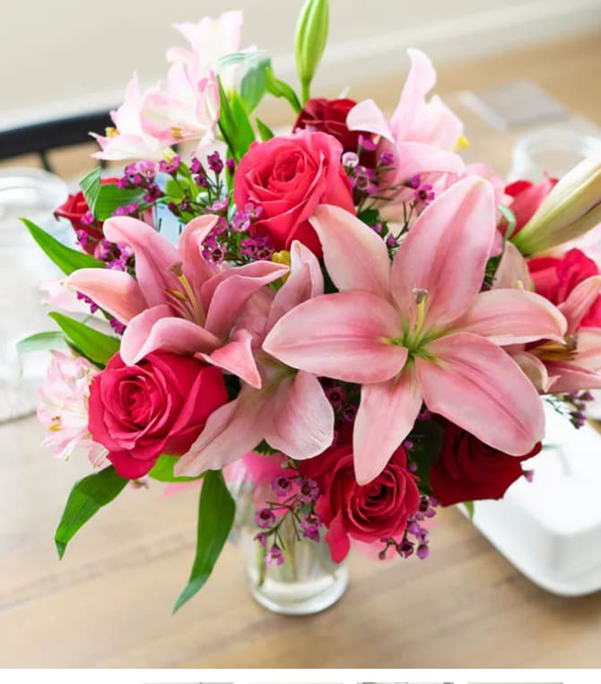 Pink lilies and red roses arranged in a clear glass vase