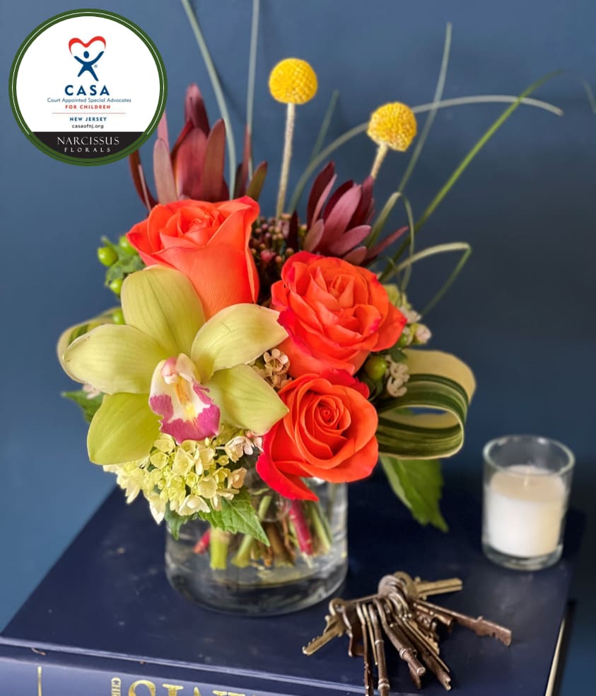 Orange roses and a pale green orchid in a glass vase