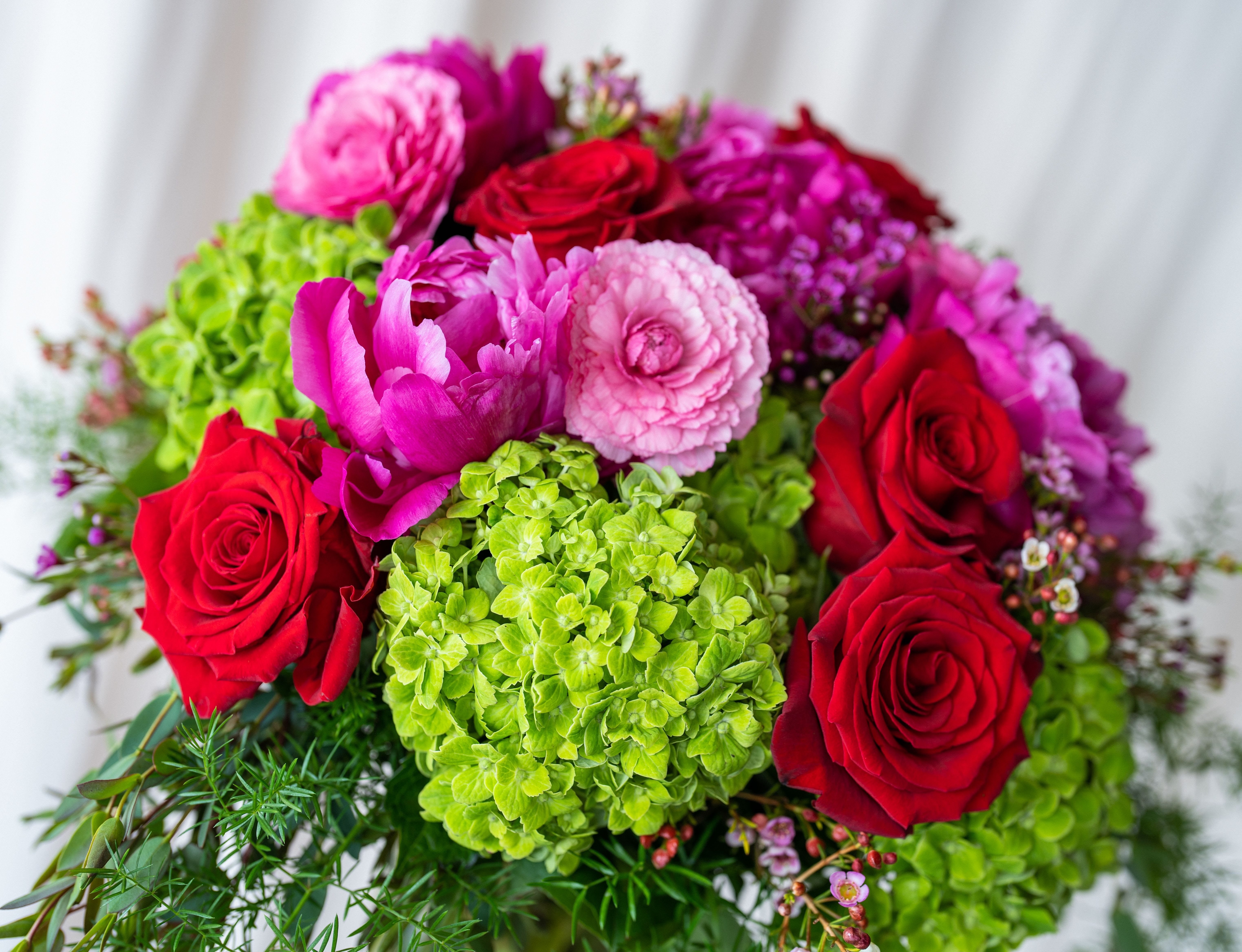 Bouquet of red roses, pink blooms, and green hydrangeas