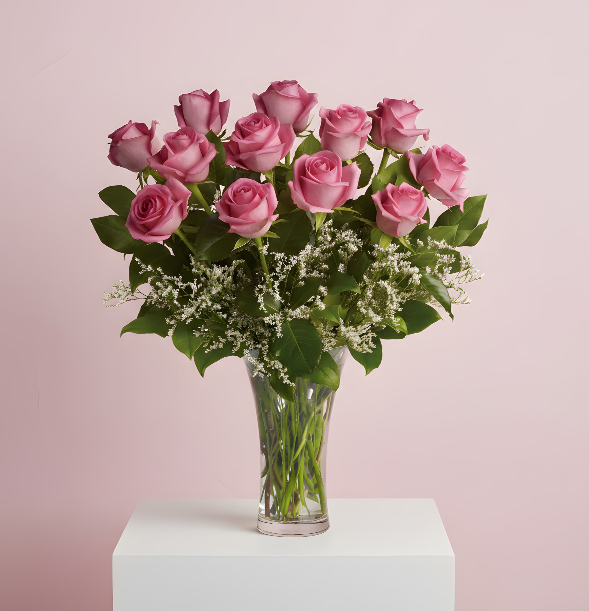 Pink roses arranged in a clear glass vase with white filler flowers