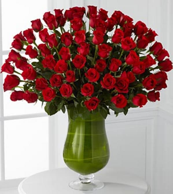 Large bouquet of red roses in a green glass vase