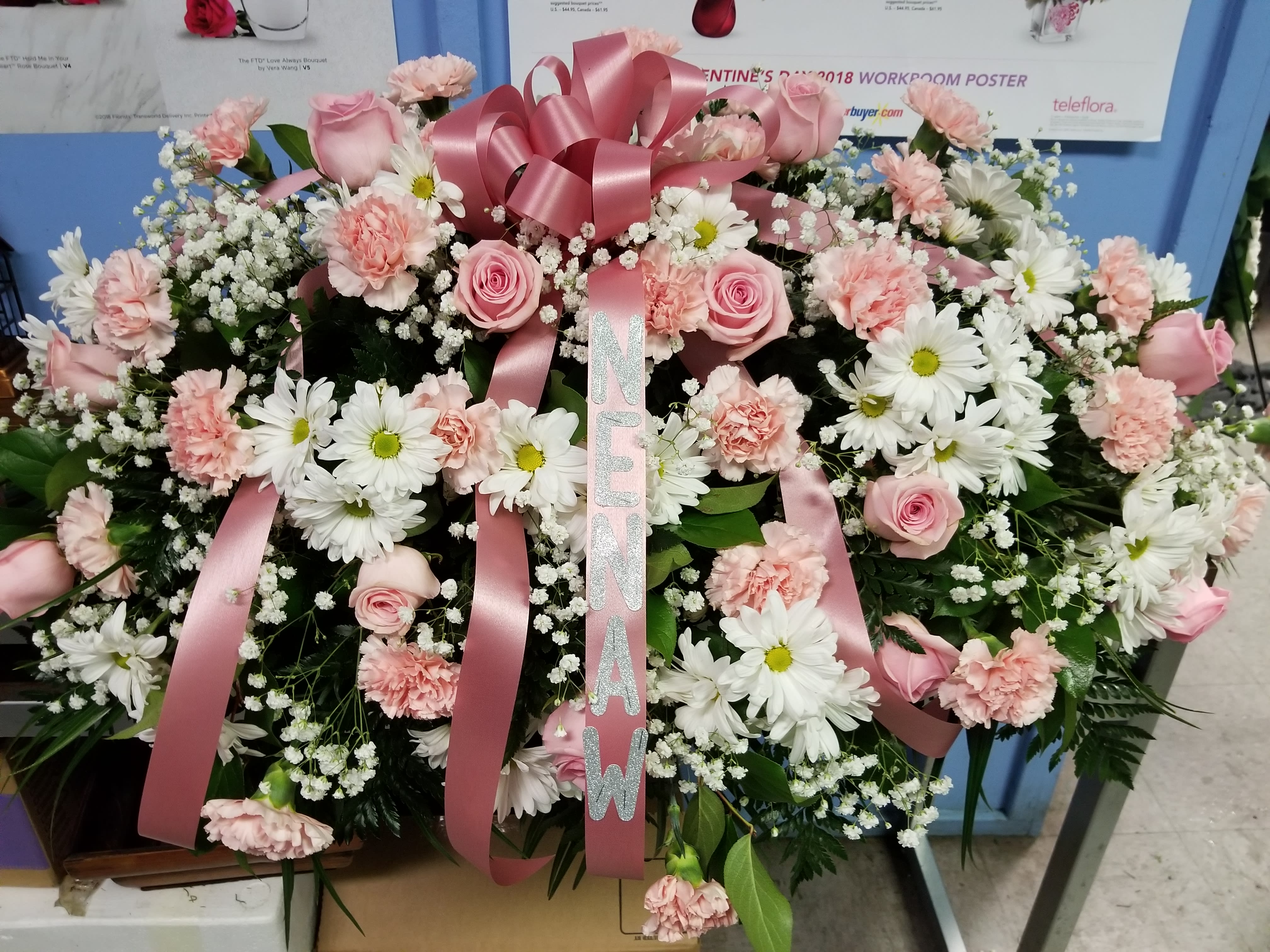Pink and white funeral spray with roses, carnations, and daisies