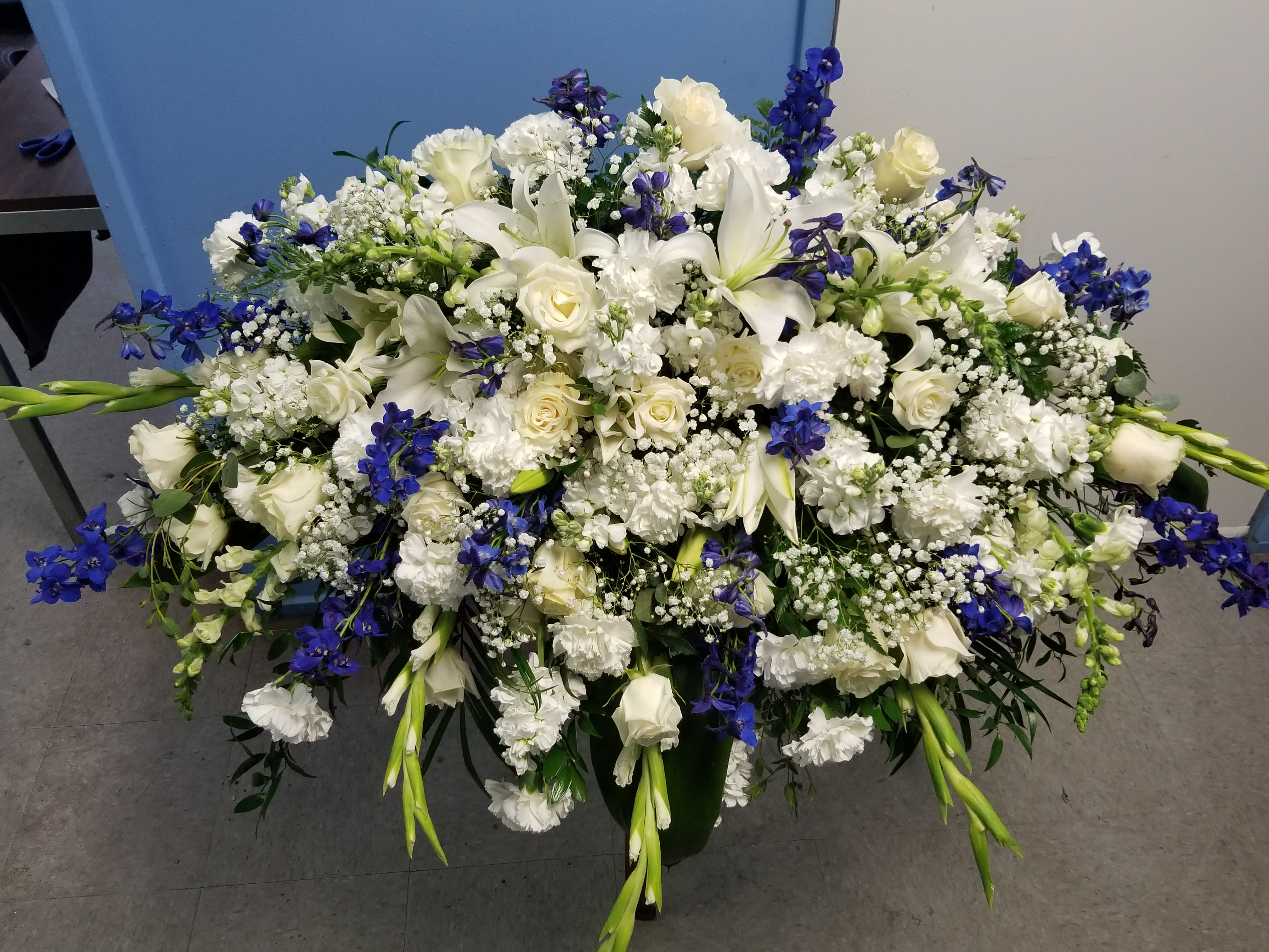 Large white and blue floral arrangement in a dark container