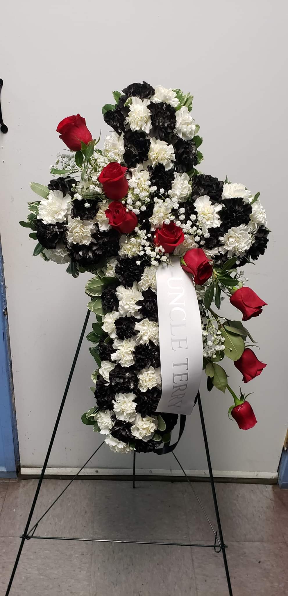 Standing floral cross with red roses and black-and-white carnations