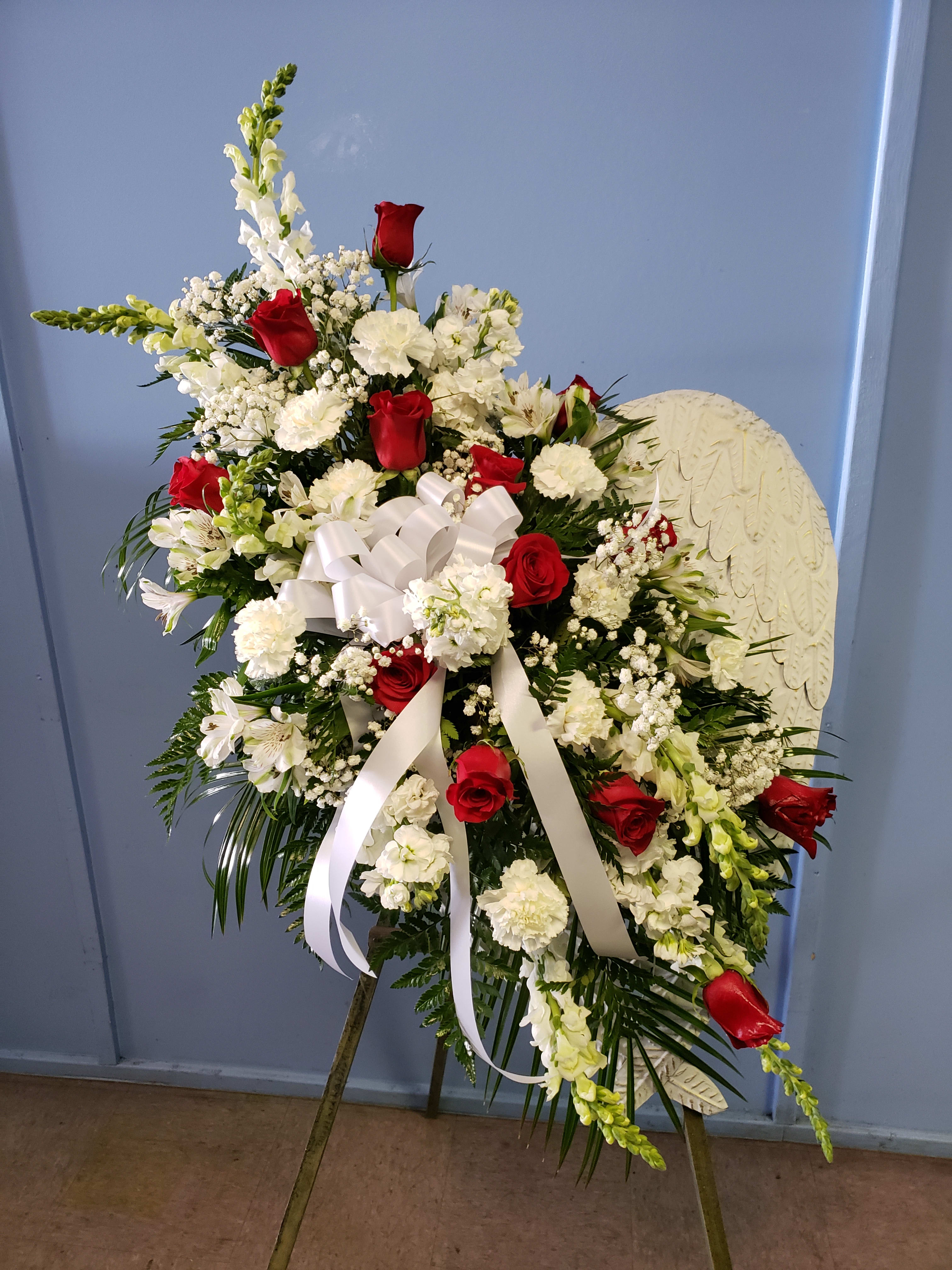 Standing floral spray with red roses and white flowers on an easel