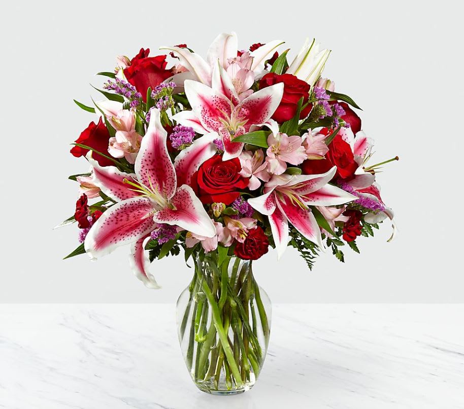 Bouquet of pink lilies and red roses in a clear glass vase