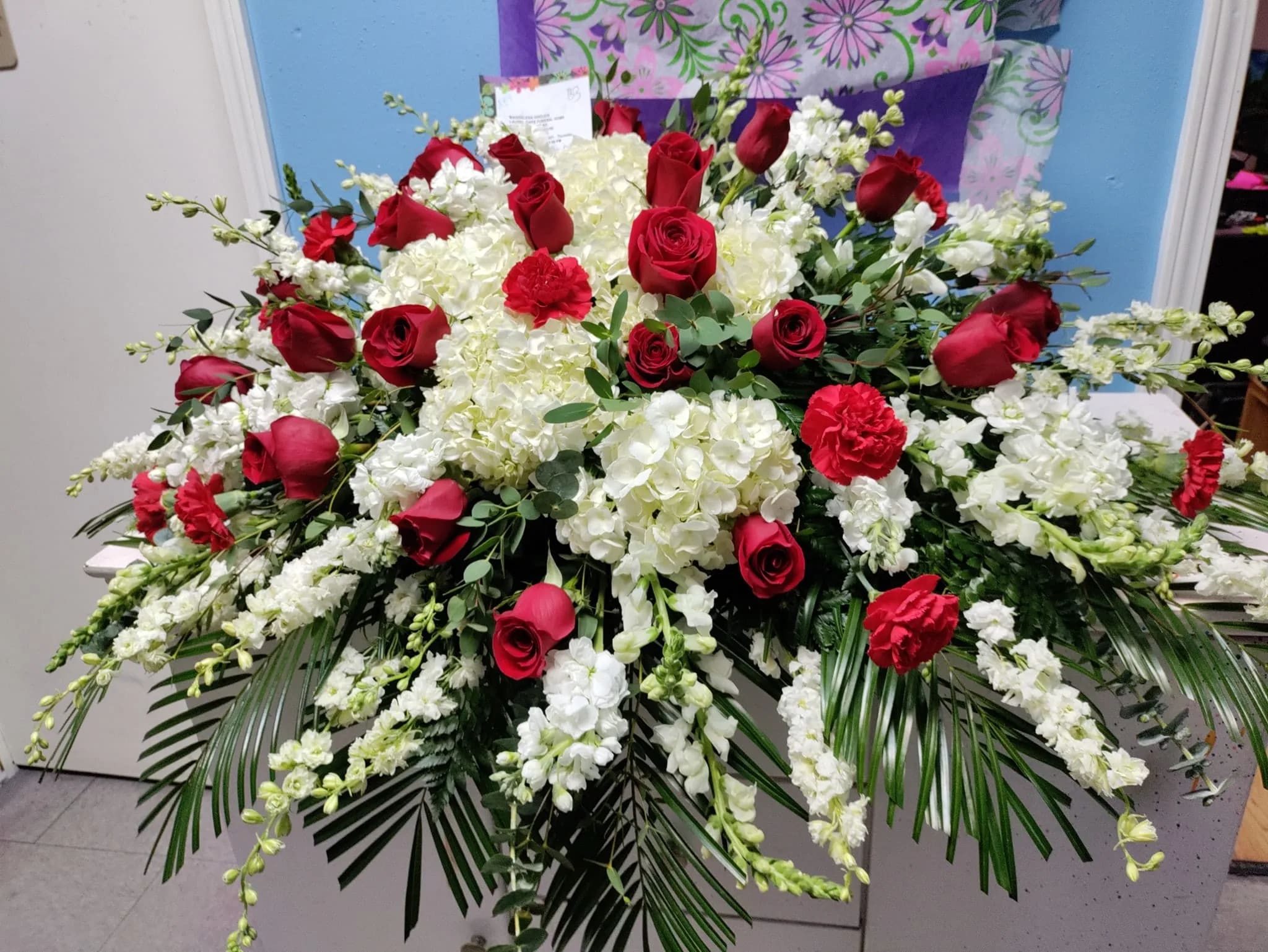 Large red rose and white floral arrangement with cascading greenery