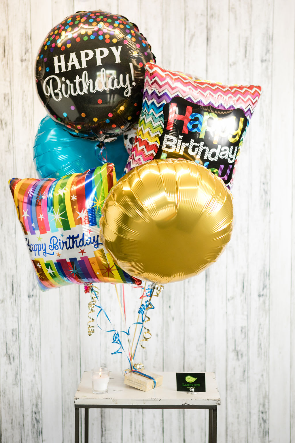 Cluster of birthday balloons with a candle and small gift on a table