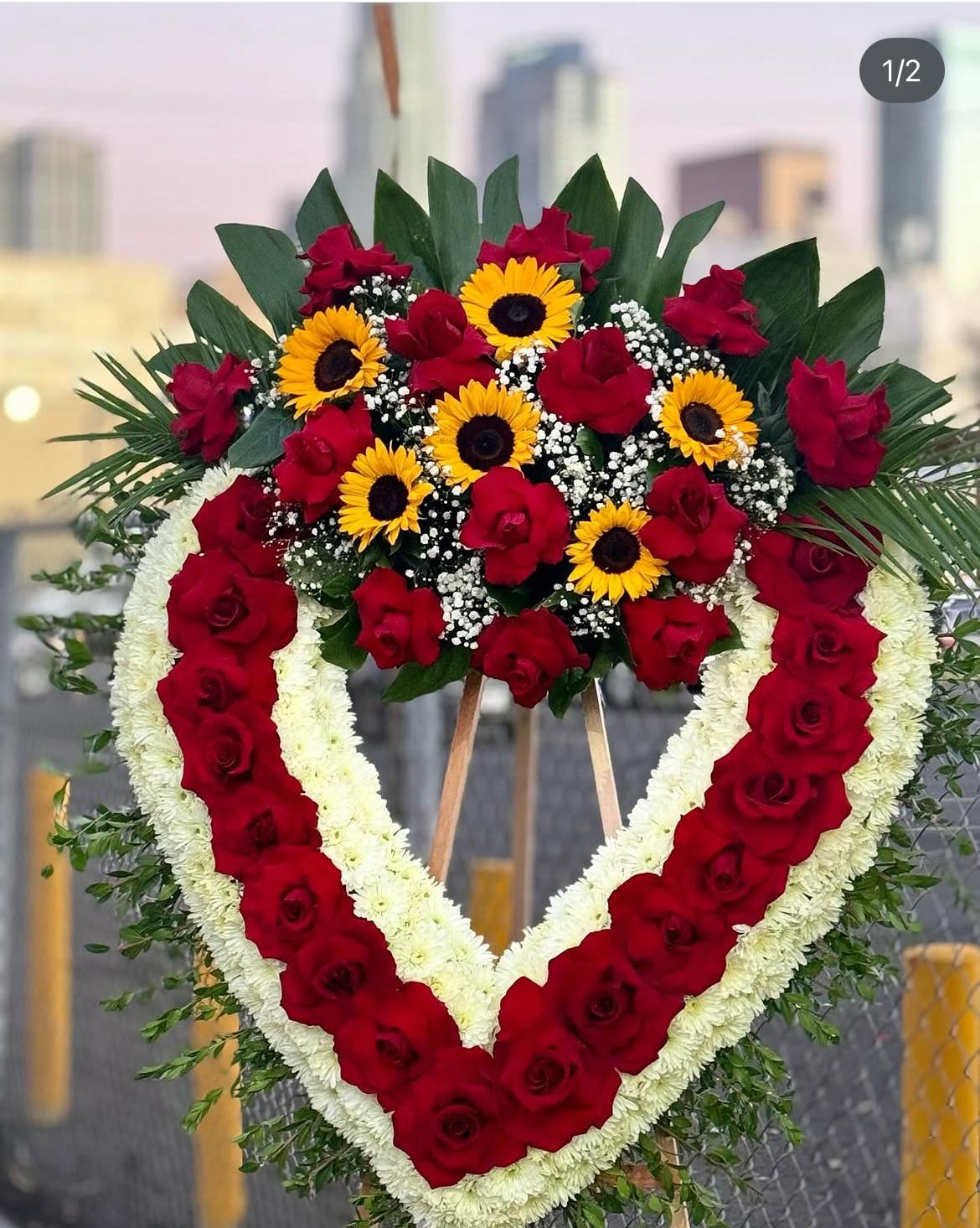 Heart-shaped floral wreath with red roses, white flowers, and yellow sunflowers
