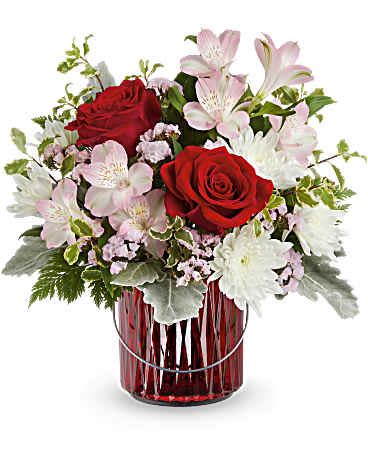 Red roses and pale pink flowers in a red glass vase