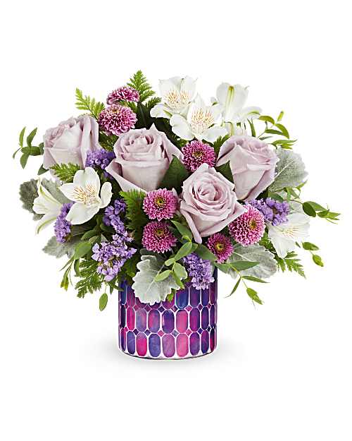 Whimsical Lovelies Bouquet - Teleflora's Whimsical Lovelies Bouquet delights with soft pastel blooms arranged in Teleflora's Bedazzling Beauty Mosaic. This charming flower arrangement doubles as a sparkling votive after the flowers are gone-perfect for birthdays, celebrations, or everyday joy. Teleflora's Whimsical Lovelies Bouquet is a charming pastel flower arrangement featuring lavender roses, white alstroemeria, lavender button spray chrysanthemums, and lavender sinuata statice, accented with dusty miller, parvifolia eucalyptus, and leatherleaf fern, delivered in Teleflora's Bedazzling Beauty Mosaic keepsake. Orientation: All-Around 