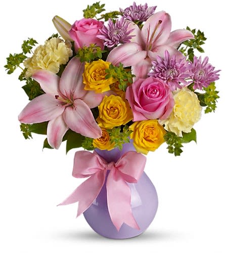 Pink and yellow mixed bouquet in a lavender vase with a pink ribbon