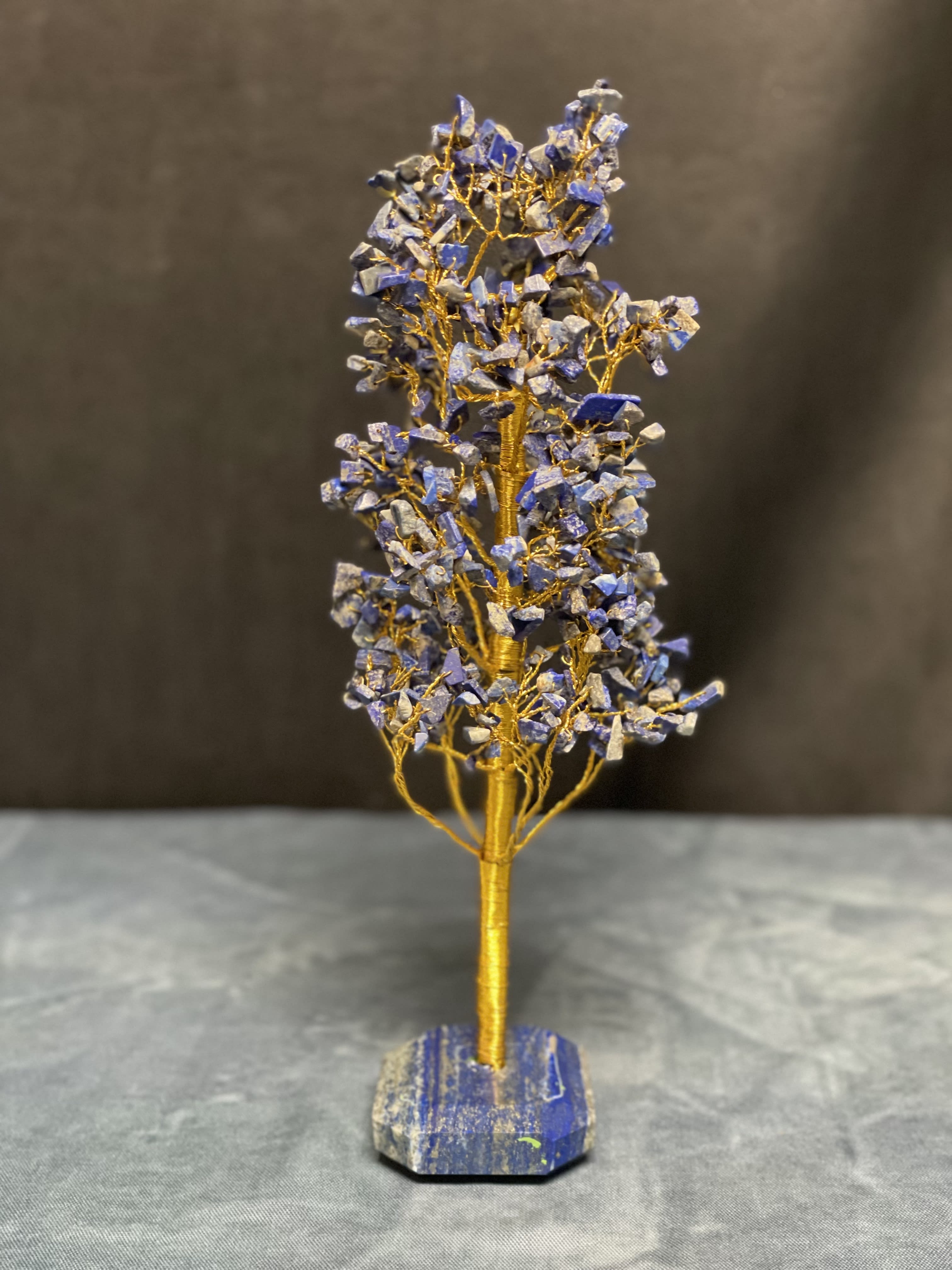 Decorative wire tree with blue stone chips on a matching stone base
