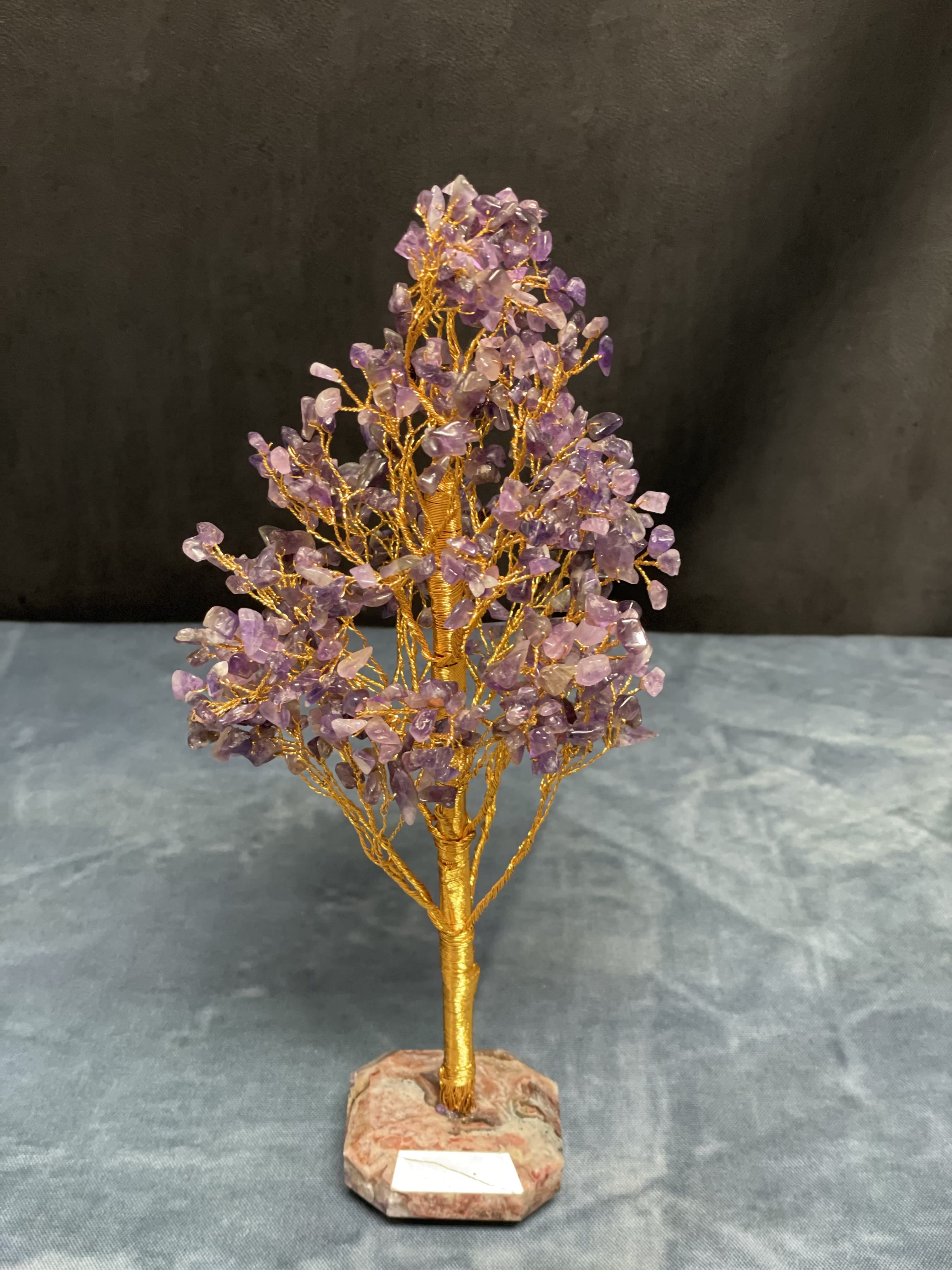 Gold wire gemstone tree sculpture with purple crystal chips on a stone base