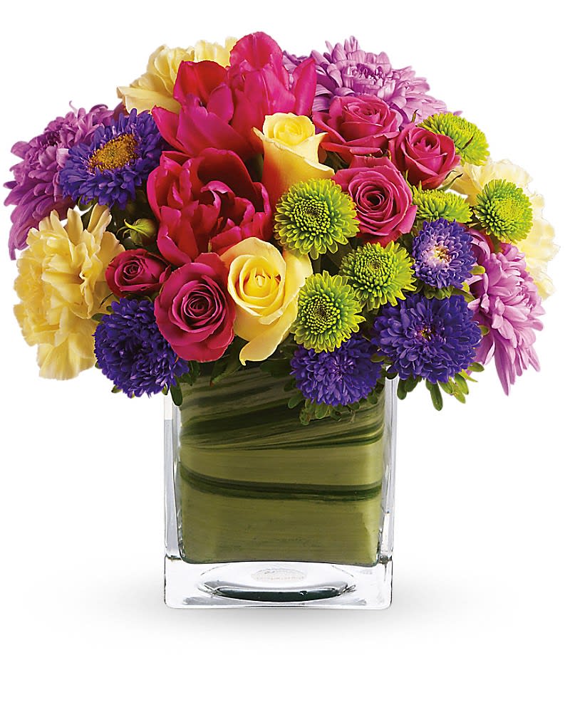 Teleflora's One Fine Day - Oh, what a fine day it will be when you have this delightful spring bouquet delivered to someone special. Everyone will delight in the vibrant colors and bountiful blossoms, all thoughtfully arranged in a beautiful leaf-lined vase. Light yellow roses, hot pink spray roses, tulips and gerberas, yellow carnations, green button spray chrysanthemums and lavender cushion spray chrysanthemums are delivered in an exclusive cube vase. You'll have many fine days when you send this beautiful bouquet!Approximately 9 1/4" W x 9 3/4" H