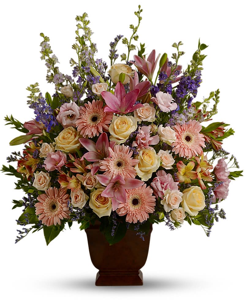 Large pastel arrangement of pink lilies, gerbera daisies, and roses in a dark pedestal vase