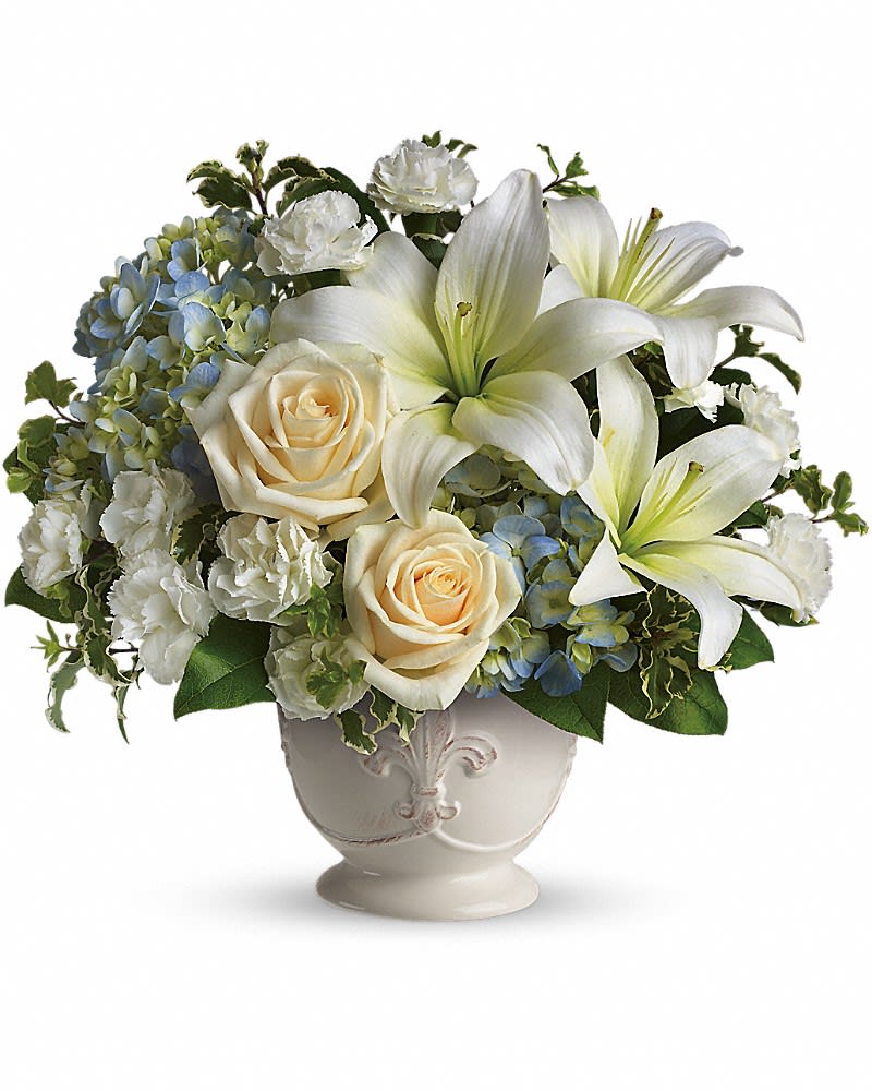 Low white ceramic bowl with white lilies, cream roses, white carnations, and blue hydrangeas