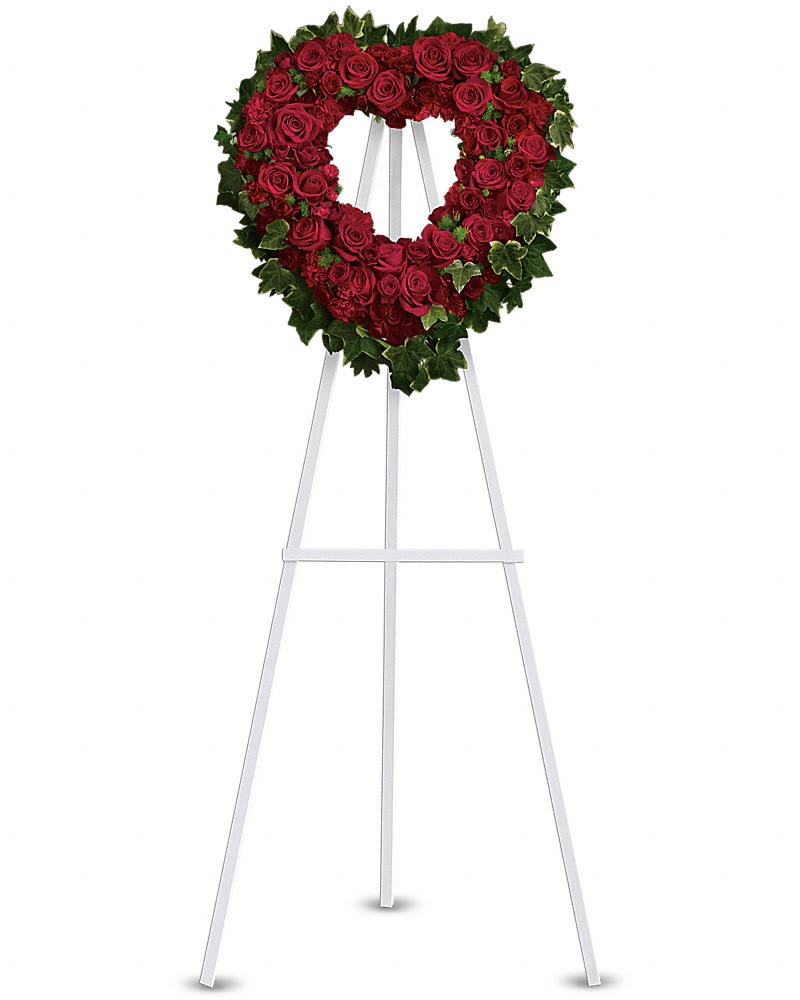 Heart-shaped wreath of red roses with ivy border on a tall white easel stand