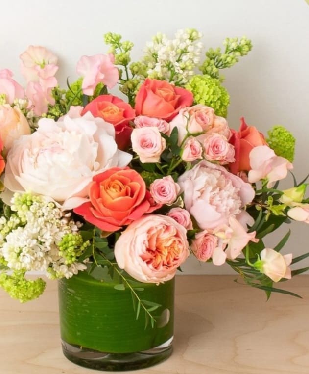 Pink and coral roses arranged in a green glass vase