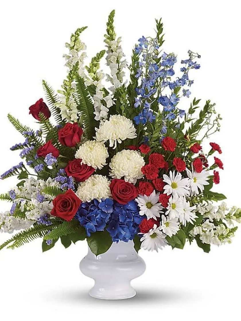 Mixed red, white, and blue floral arrangement in a white vase