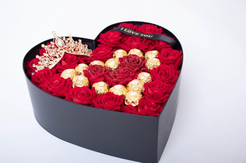 Heart-shaped box of red roses with gold chocolates and a tiara