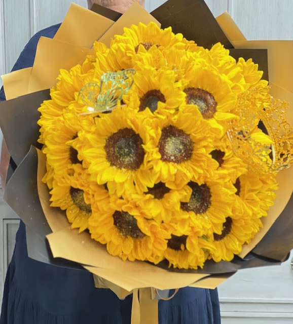 Bouquet of bright yellow sunflowers wrapped in black and gold paper