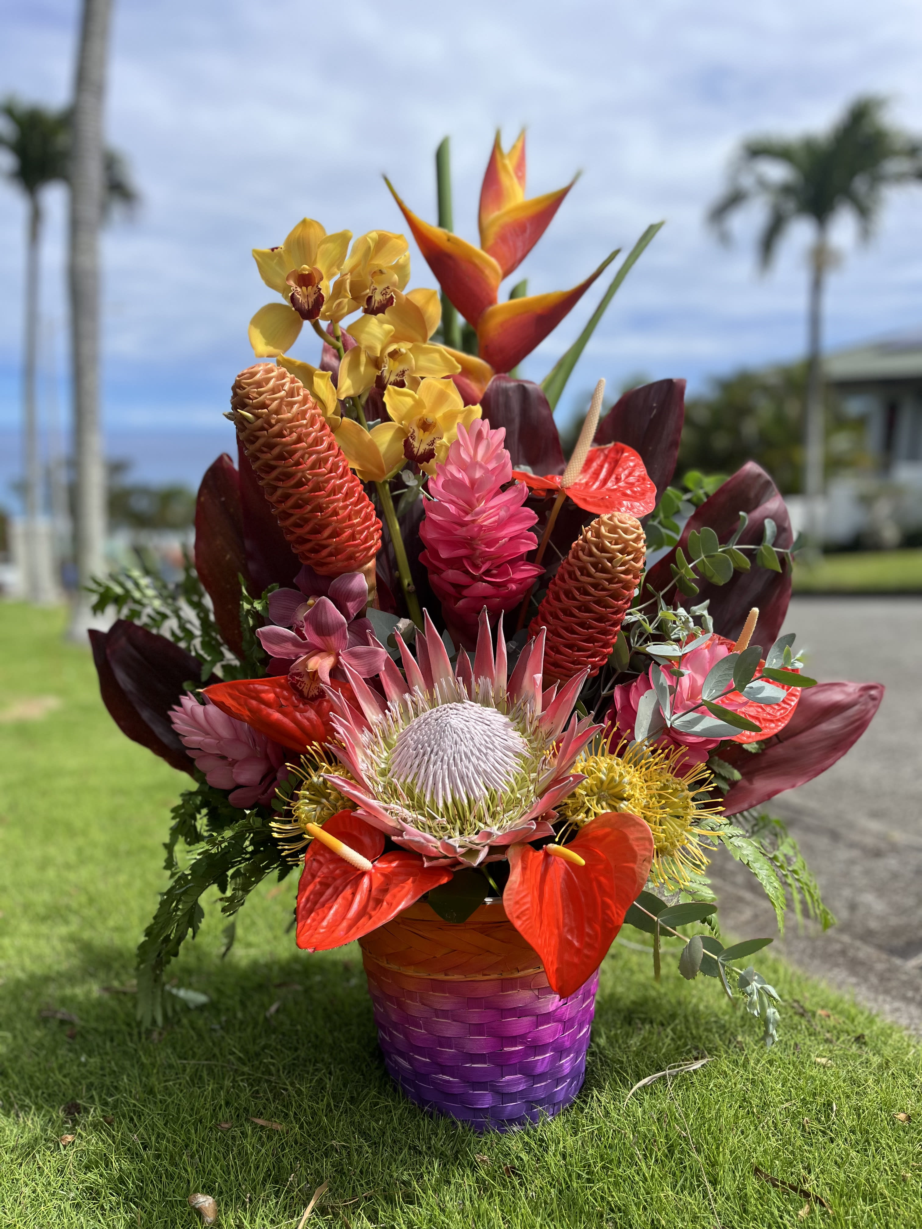 Sunset Spectacle (OAHU ONLY) - Introducing "Sunset Spectacle" - a captivating sunset-themed flower basket inspired by the breathtaking sunsets of Hawaii. This enchanting arrangement is designed to give you or your loved ones the feeling of a magical Hawaiian sunset, adorned with the freshest locally sourced blooms from Hawaii.  Immerse yourself in the radiant hues of the tropics with "Sunset Spectacle." Each bloom is carefully selected to capture the essence of a Hawaiian sunset, ensuring that every petal reflects the vibrant colors and tranquility of those mesmerizing evenings.  Whether it's a gift for someone special or a treat for yourself, "Sunset Spectacle" promises to transport you to a world of tropical splendor. Experience the warmth, tranquility, and sheer magic of a Hawaiian sunset, right in the comfort of your own space. Let the captivating Hawaiian blooms ignite your senses and infuse your surroundings with the unforgettable ambiance of a sunset paradise.
