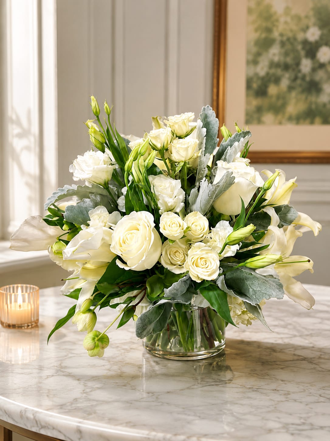 Petal Perfection‘s Wondrous White - Creamy white roses, fragrant lilies, and delicate lisianthus form a serene, rounded bouquet that reads as calm elegance - perfect as a sympathy arrangement, anniversary flowers, or a refined Mother's Day gift. This white flower arrangement also suits weddings, thank-you gestures, and "just because" moments when you want the person you're thinking of to feel comforted and truly seen.  The compact design clusters roses, spray roses, lilies, and lisianthus closely for a lush, tactile look, with soft green buds woven in to add subtle contrast. Blooms are presented in a simple clear glass vase that keeps the focus on texture and form; the clean lines make it equally at home on a bedside table, mantel, or dining centerpiece. Sized to be both intimate and impactful, it's a tasteful choice for Easter, graduations, housewarmings, sympathy and funeral services, or holiday and seasonal gift-giving.  Easy to care for: refresh the water every 2-3 days, recut stems at an angle, and keep out of direct heat to extend vase life. Available for same-day delivery when ordered early, it's a graceful way to mark birthdays, get well wishes, weddings, retirements, and other meaningful milestones.