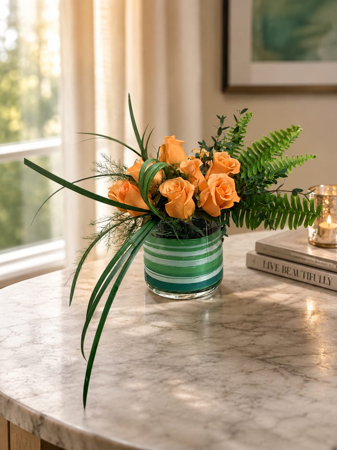 Orange roses in a striped glass vase with long green foliage