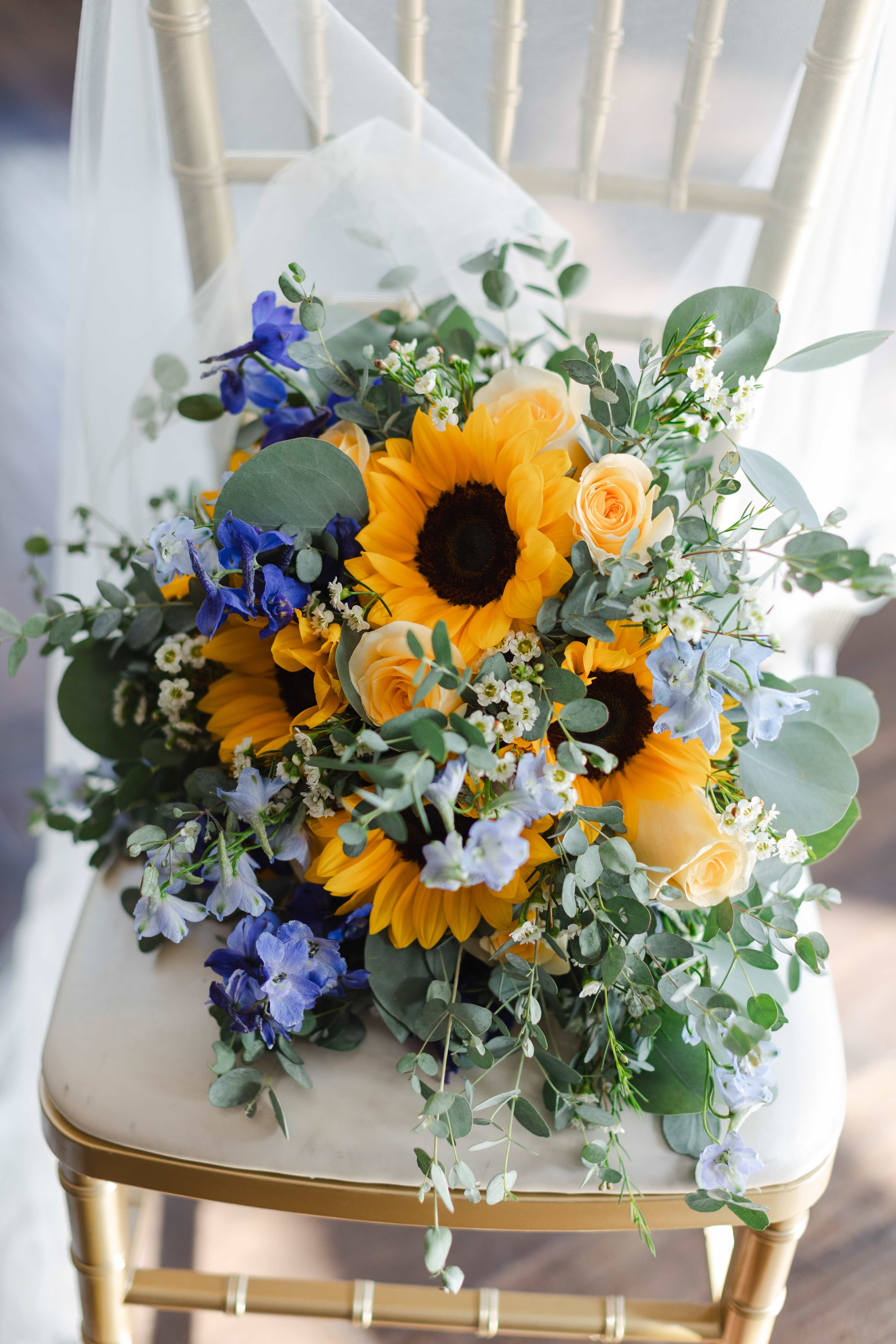 Bouquet of sunflowers, peach roses, and blue flowers on a chair