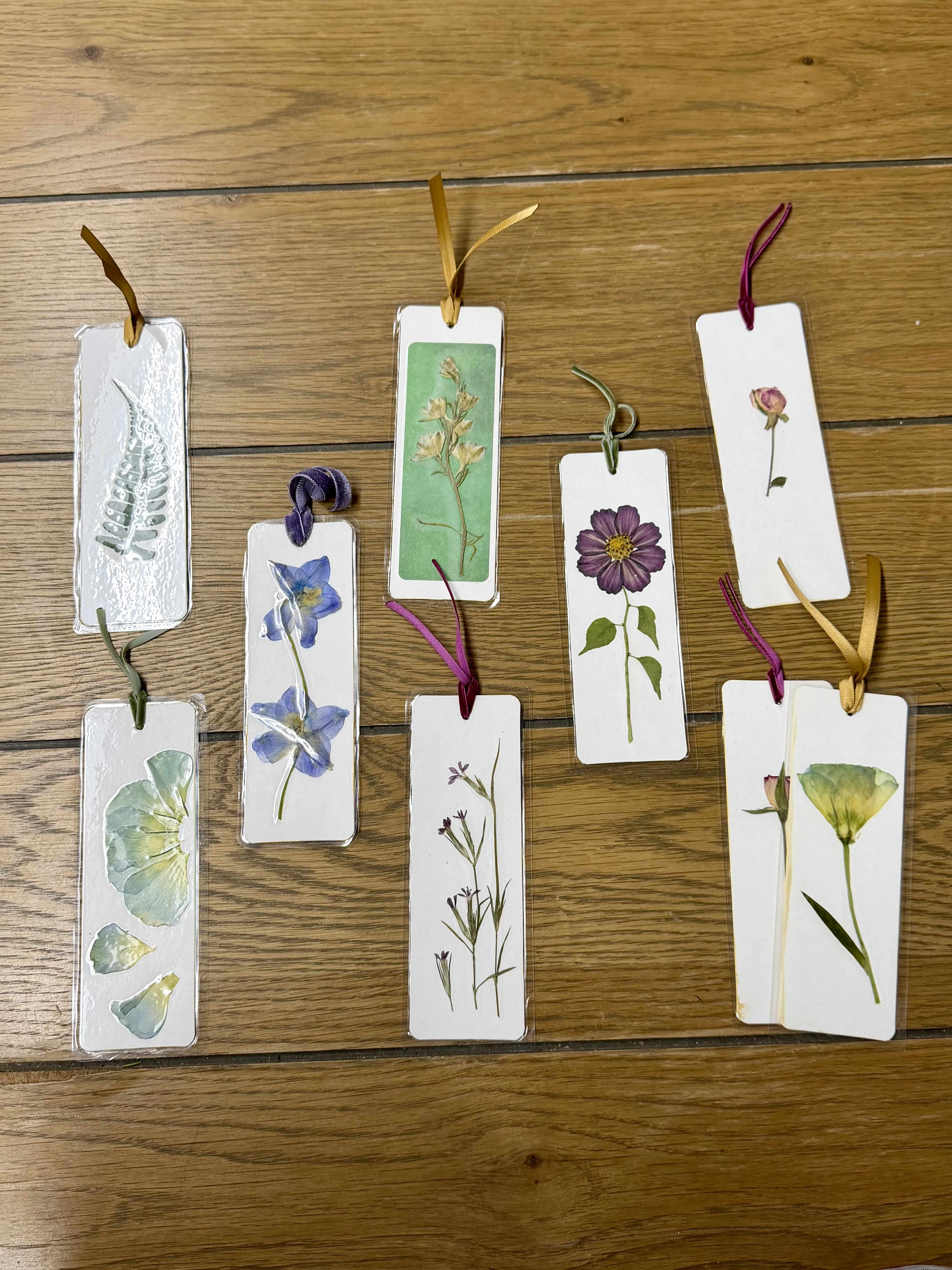 Pressed flower bookmarks tied with ribbons on a wooden surface