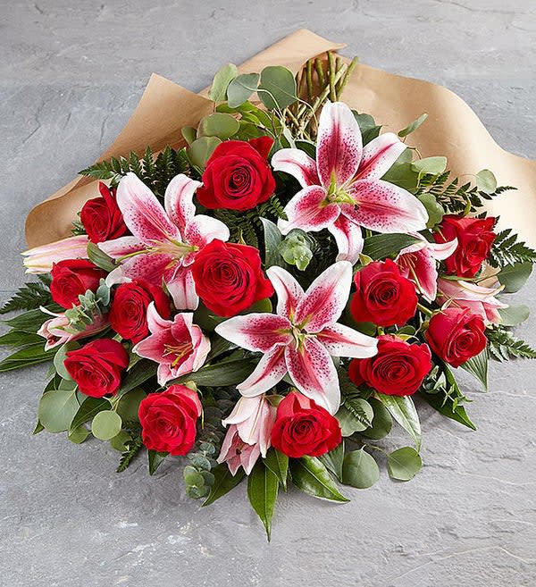 Bouquet of red roses and pink lilies wrapped in tan paper