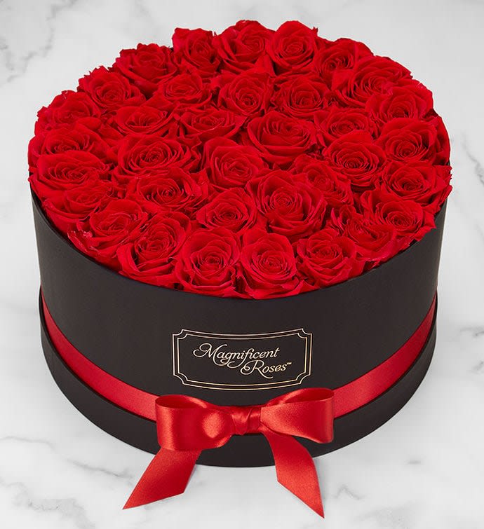 Round box filled with red roses and tied with a red ribbon