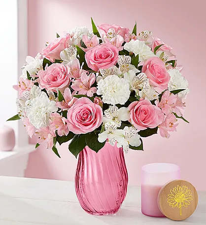 Pink roses and white flowers arranged in a pink glass vase