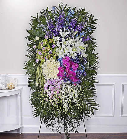 Tall standing floral spray with white lilies, orchids, and purple flowers