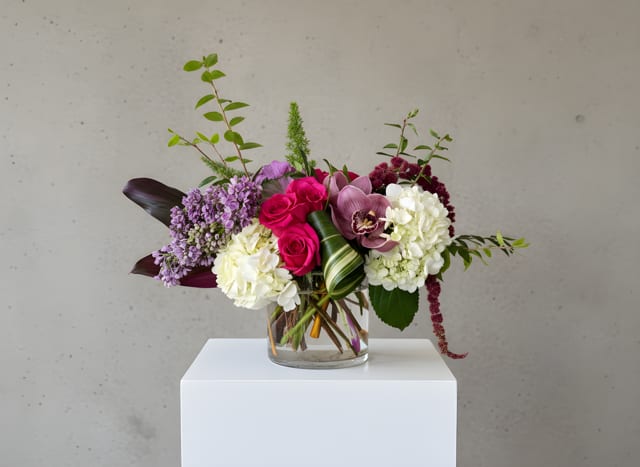 Mixed bouquet of pink, white, and purple flowers in a clear glass vase