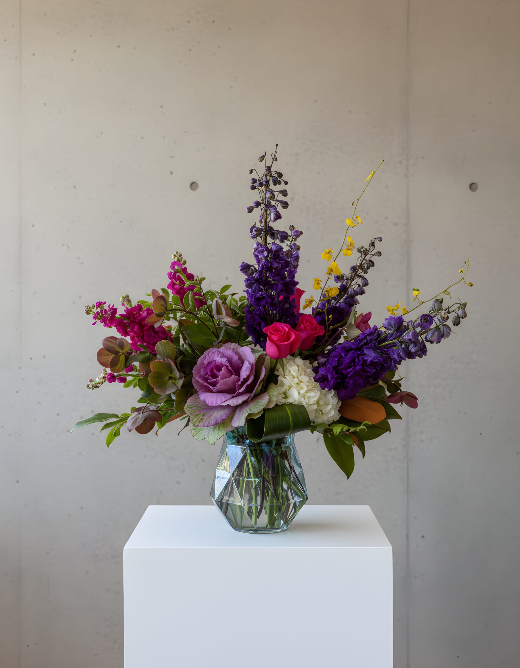 Mixed bouquet of purple, pink, and white flowers in a glass vase